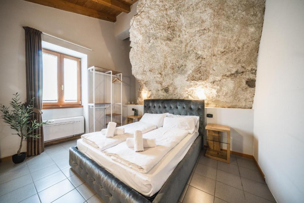 a bedroom with a large bed in a stone wall at La Cantinota - Locanda De Manincor Rooms in Arco
