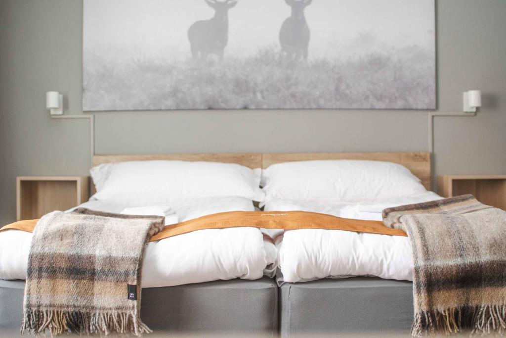 1 cama con almohadas blancas y una pintura en la pared en Storlien Högfjällshotell AB, en Storlien