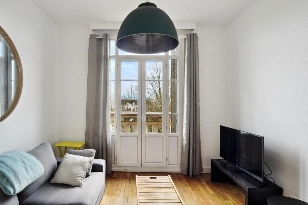 un salon avec un canapé et une grande fenêtre dans l'établissement Sublime Appart Tout Confort Centre Ville Gare, à Troyes