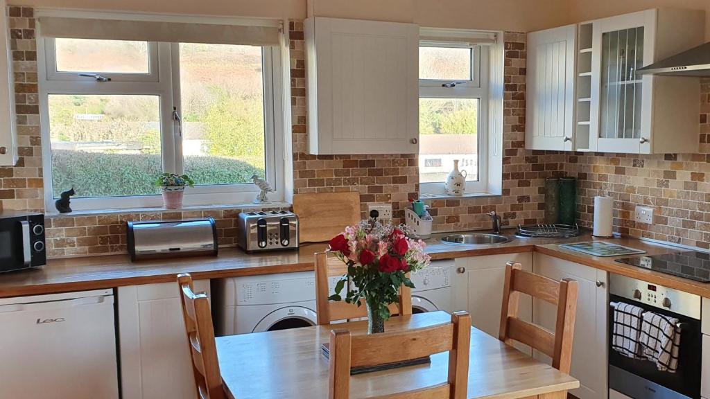 a kitchen with a table with a vase of flowers on it at Granny Shells in The Mumbles