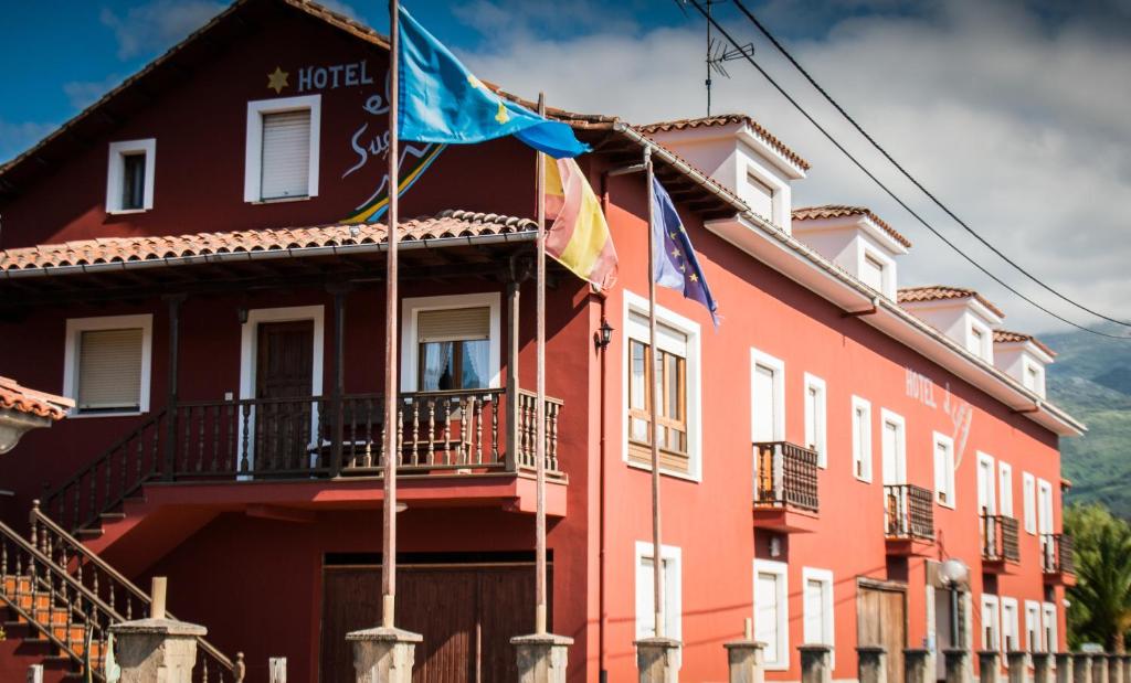 ein rotes Gebäude mit Flaggen davor in der Unterkunft Hotel El Sueve in Colunga