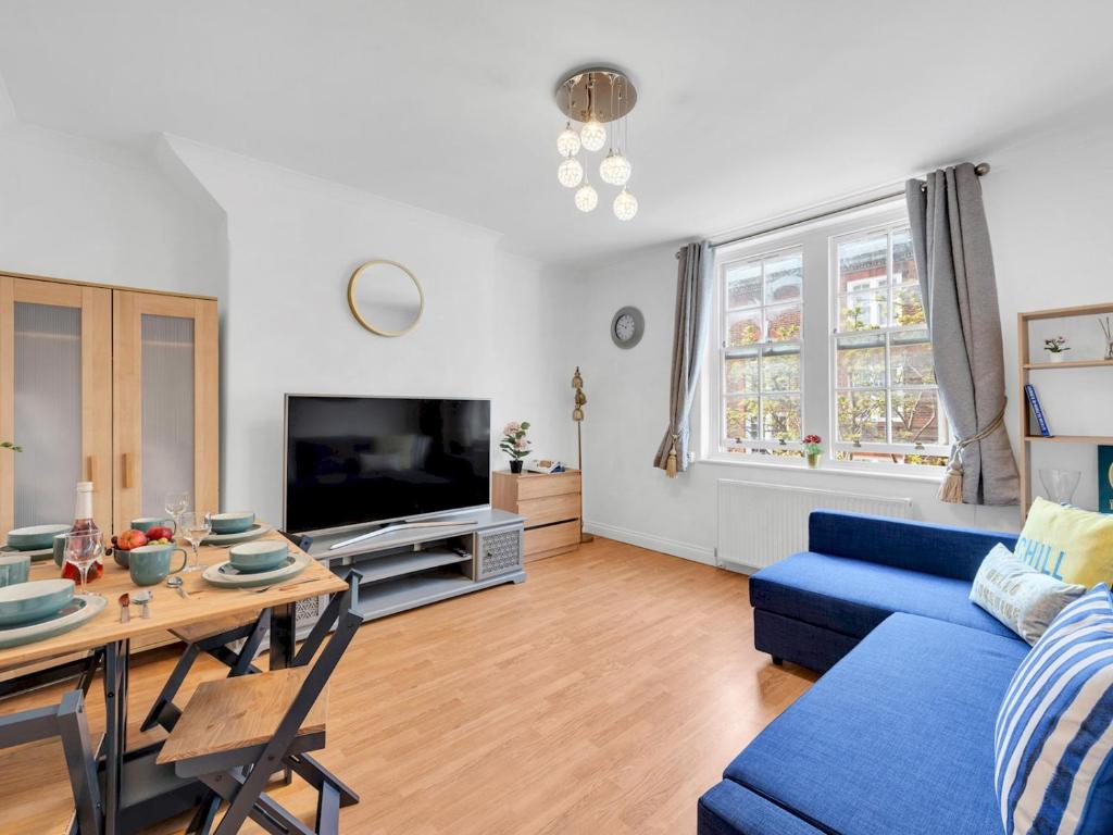 ein Wohnzimmer mit einem blauen Sofa und einem Tisch in der Unterkunft Pass The Keys - Spacious Modern 2BR Flat for 6, 3min walk to Hammersmith Station in London