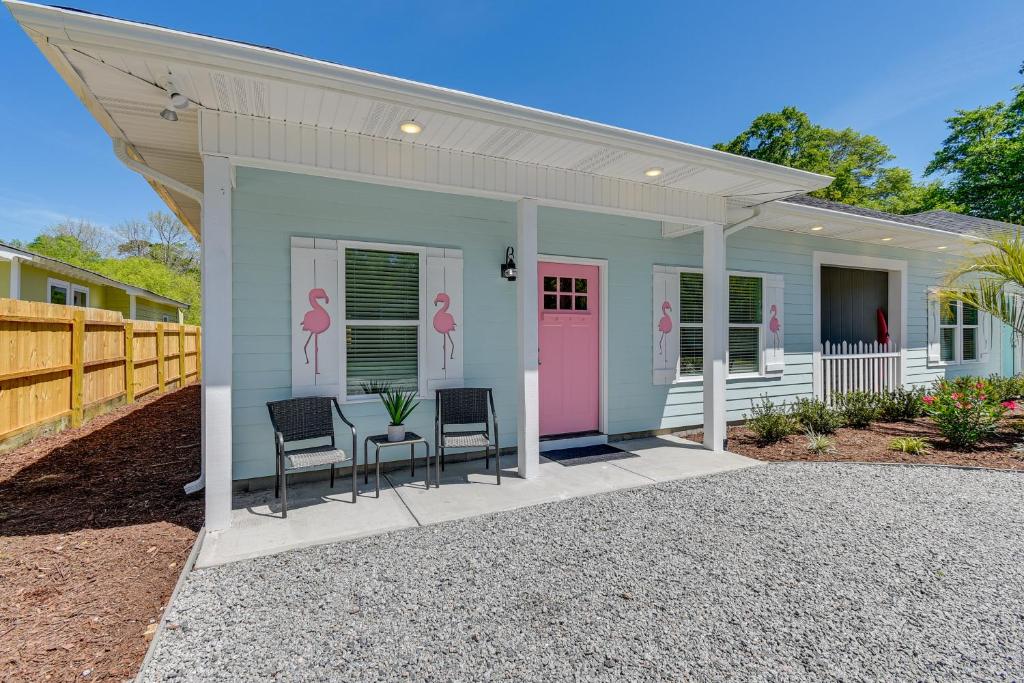 a small house with two chairs and a pink door at Lovely Vacation Home about 1 Mi to Ocean Isle Beach! in Ocean Isle Beach