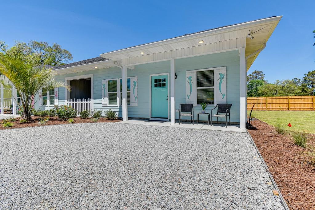 a house with a blue door and chairs on a gravel driveway at Charming Ocean Isle Beach Home about 1 Mi to Beach! in Ocean Isle Beach