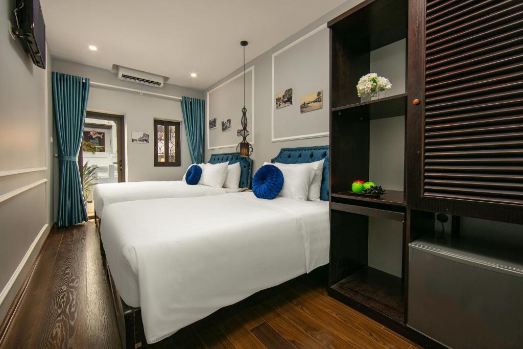 a bedroom with two beds with blue and white pillows at La Renta Hotel & Spa in Hanoi