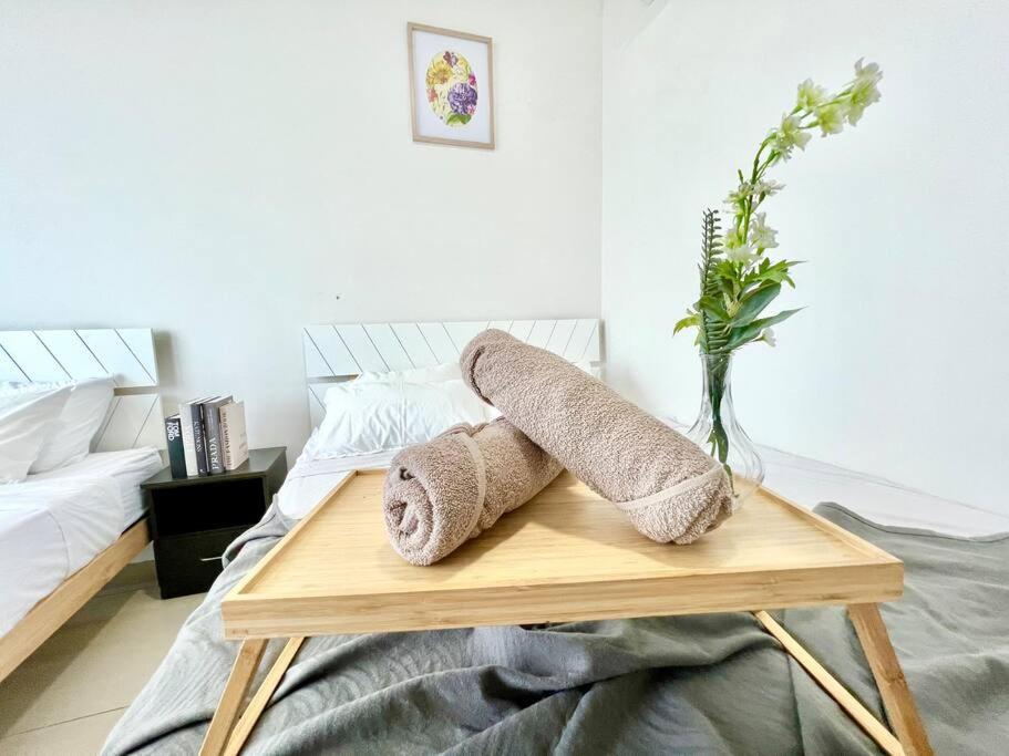 un tavolo in legno con asciugamani sopra un letto di N Cozy 1-10Pax 2Room Trefoil SetiaAlam SmrtTV Wifi a Setia Alam