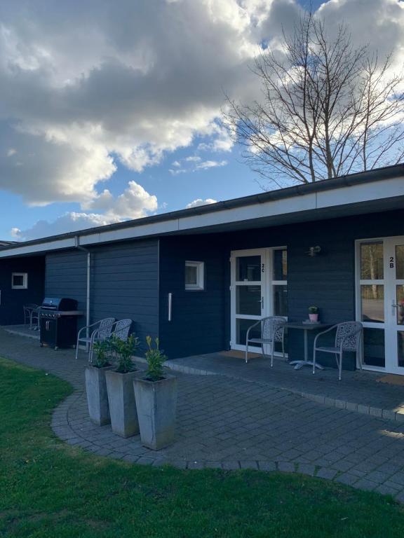 un bâtiment bleu avec des chaises et des tables devant lui dans l'établissement Vorbasse Holiday Apartments, à Vorbasse