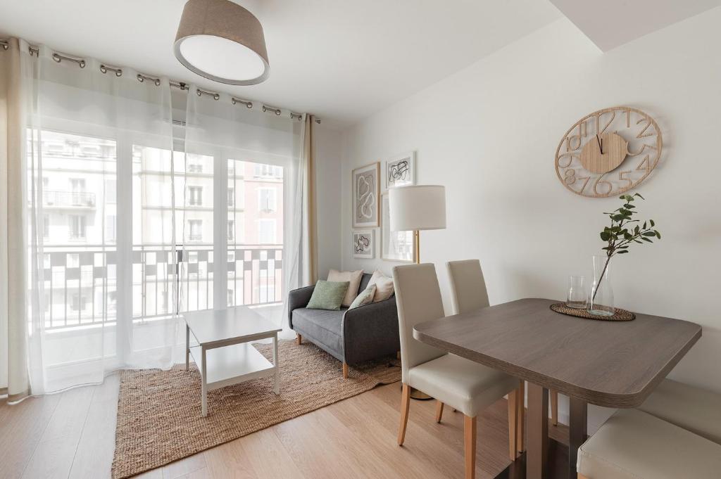 a living room with a table and a couch and a dining room at OVELIA Poissy - Les Romantiques in Poissy