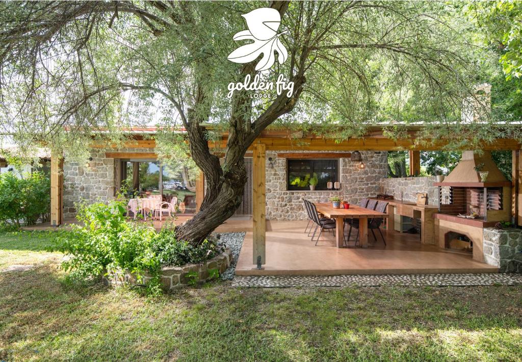 a patio with a table and a tree at Villa Menie - Golden Fig Sykia lodge in Paralia Sikias