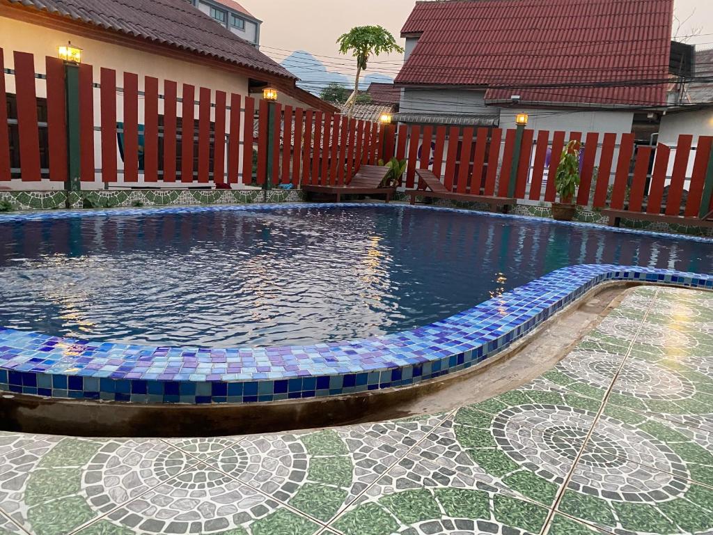 a swimming pool with a mosaic floor and a house at Premier Vang Vieng Hotel in Vang Vieng