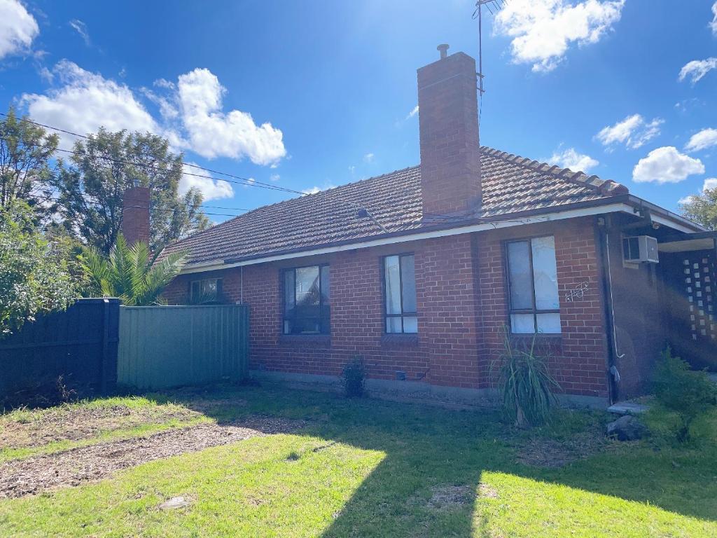 a red brick house with a chimney and a fence at Comfy Private rooms in Braybrook in Braybrook