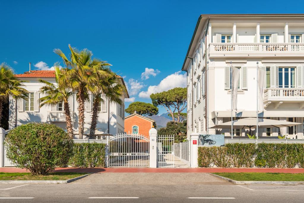 a white house with a gate and palm trees at Villa Grey in Forte dei Marmi