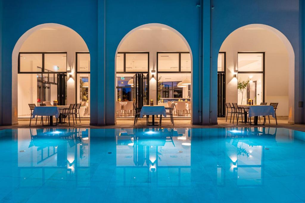 uma piscina com mesas e cadeiras num edifício em Miramare Hotel em Zadar