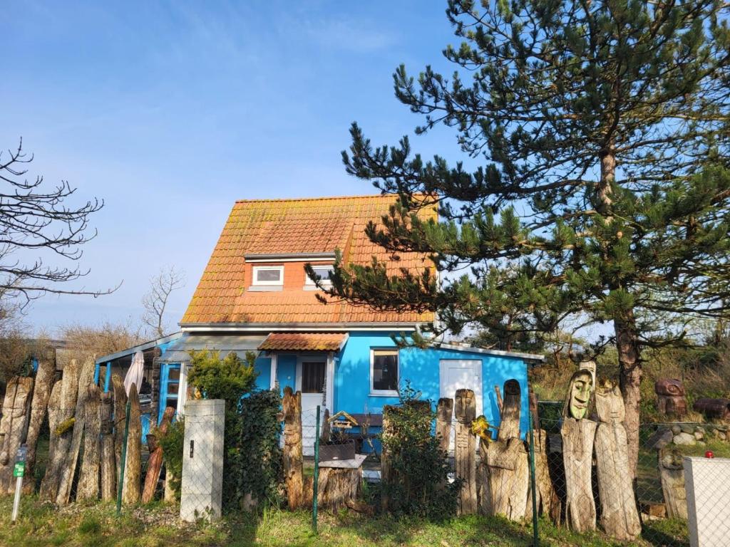une maison bleue avec une clôture devant elle dans l'établissement Ferienhaus Dünenhaus, à Dierhagen