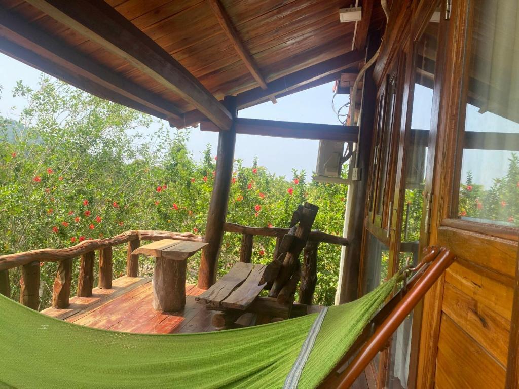 a hammock on the porch of a cabin with red flowers at Ngọc Tiên Farmer Eco Lodge Cat Tiên in Cat Tien