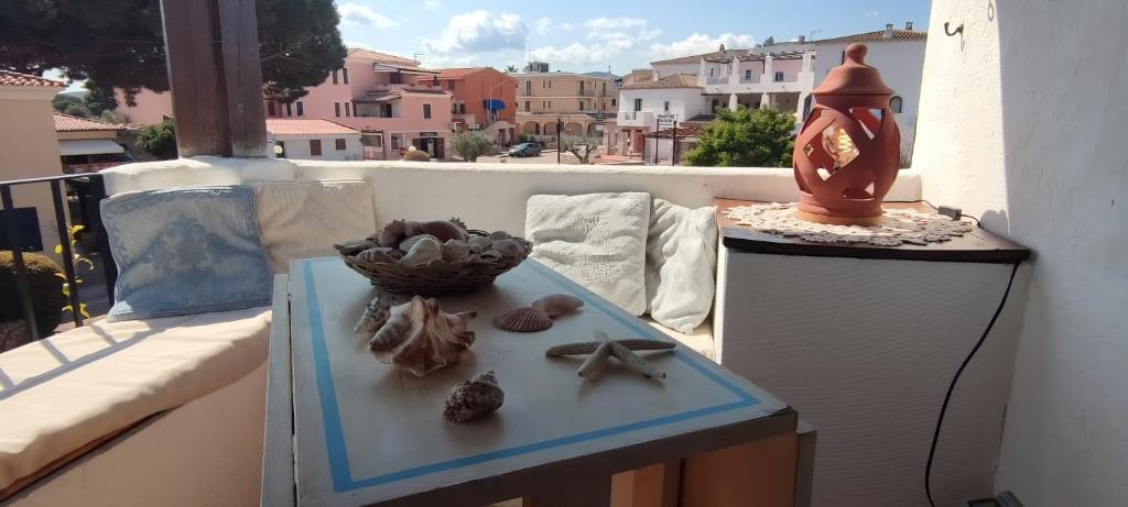 Una mesa con conchas marinas en un balcón con un reloj. en Sardegna Porto San Paolo, en Porto San Paolo