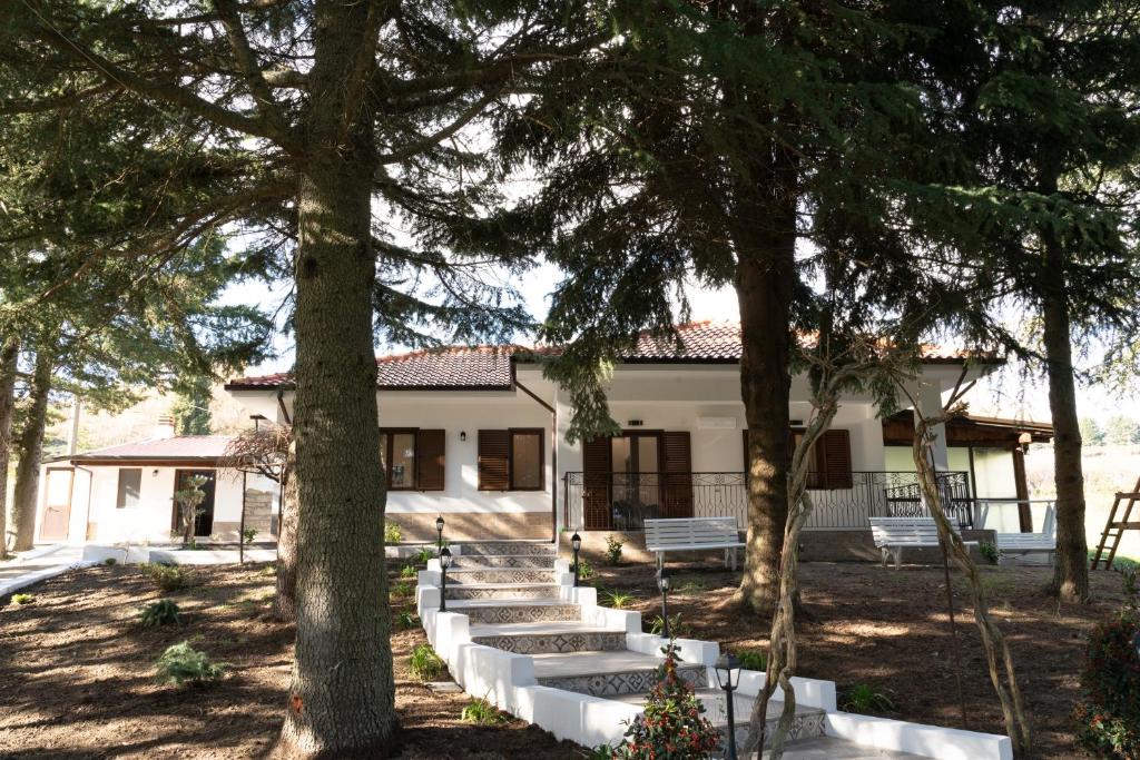 a white house with trees in front of it at B&B Tenuta Piano Campo in Ucria