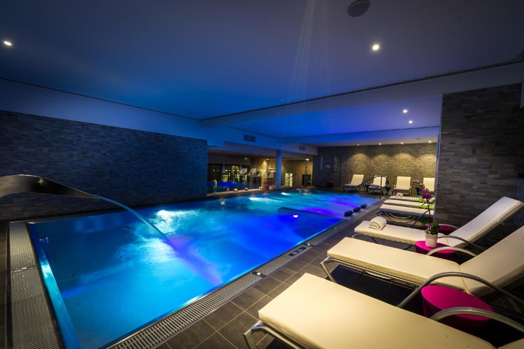 a large swimming pool in a hotel with lounge chairs at Hôtel Restaurant Athena Spa in Strasbourg