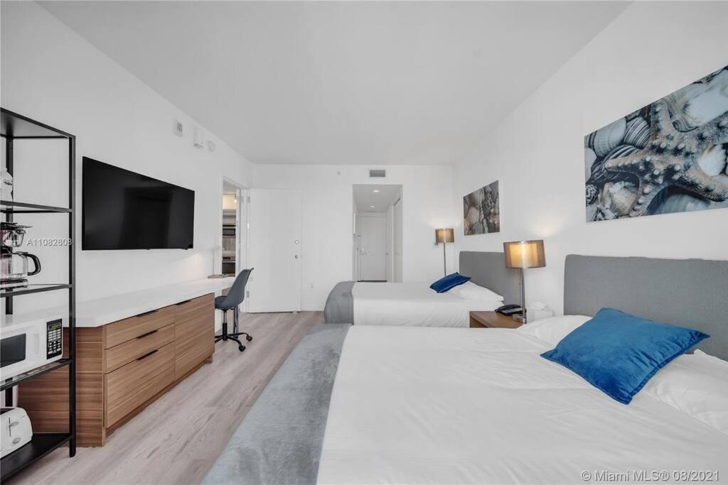 um quarto de hotel com duas camas e uma televisão de ecrã plano em BeachWalk Studio B Apmt 2 full Beds, amazing view 01B em Hallandale Beach
