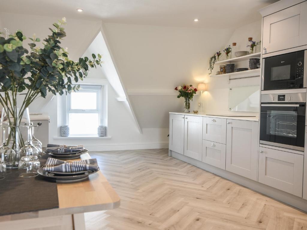 a kitchen with white cabinets and a wooden floor at Fore Street House - Apartment 3 in Seaton