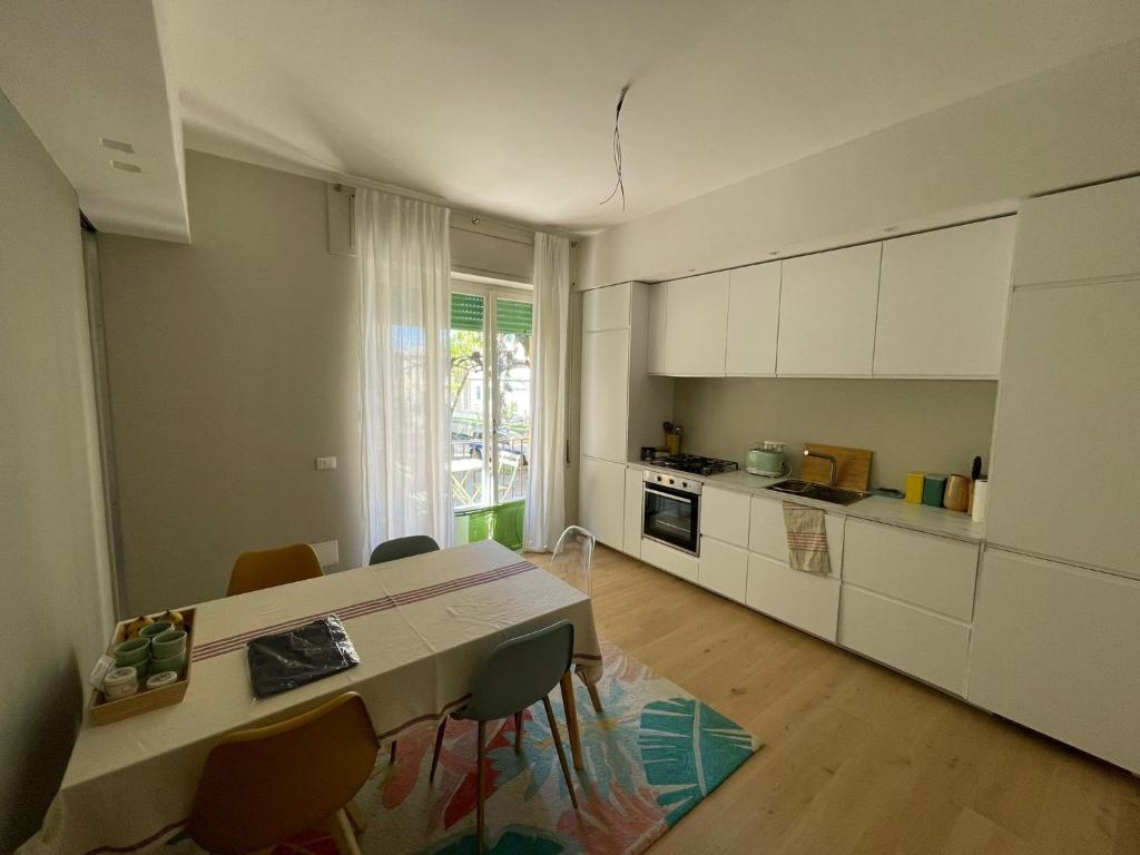 uma cozinha com armários brancos e uma mesa e cadeiras em Via Scernio 2 PT em Bonassola