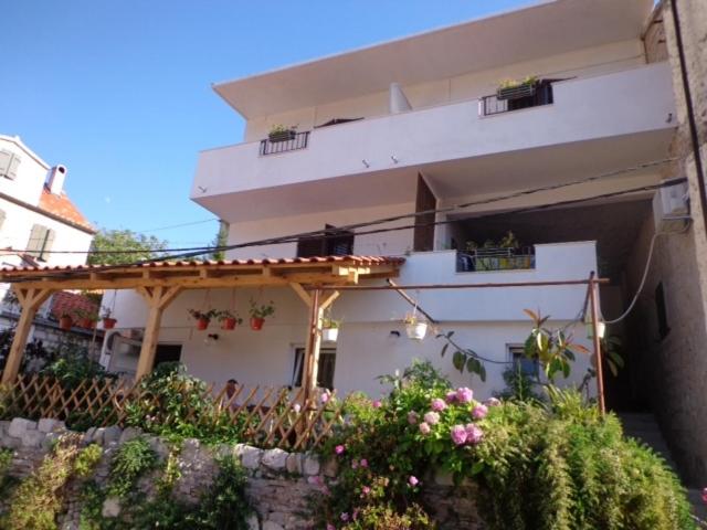 a large white building with a porch and flowers at Ana Tudor Apartments in Hvar