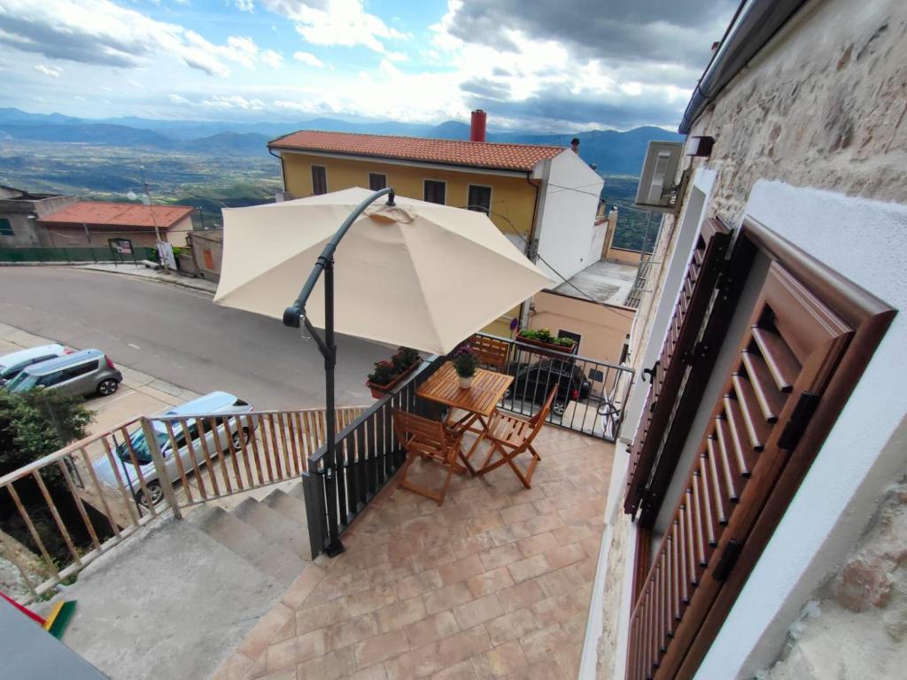 un patio con ombrellone e sedie su un balcone di Dommu de Anna Murru a Baunei