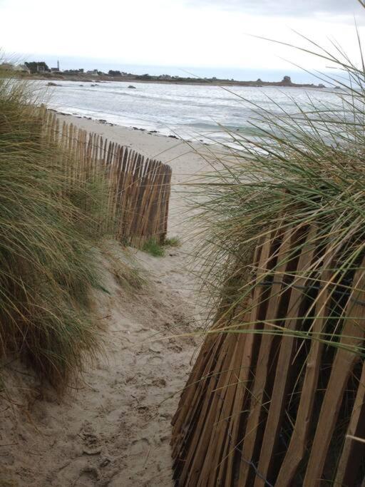 a wooden fence on a beach near the water at Kerletty, la mer, les embruns, à 250 m des plages in Plouguerneau