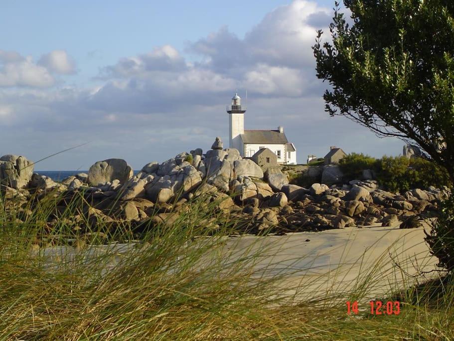 a lighthouse sitting on top of a pile of rocks at Kerletty, la mer, les embruns, à 250 m des plages in Plouguerneau