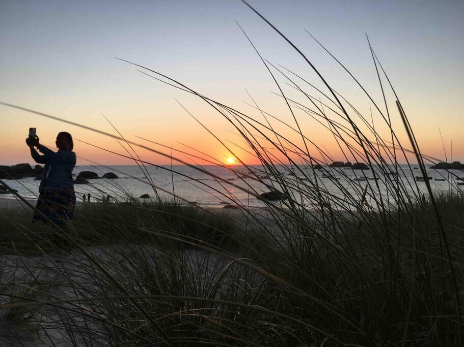 a woman taking a picture of the sunset on the beach at Kerletty, la mer, les embruns, à 250 m des plages in Plouguerneau