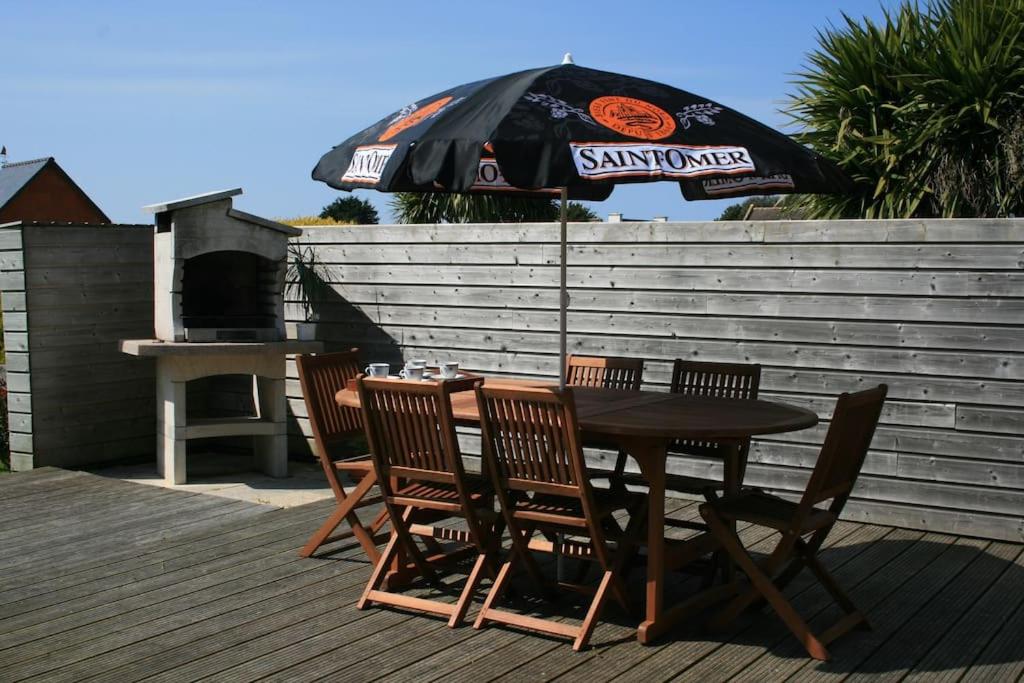 a table and chairs with an umbrella on a deck at Kerletty, la mer, les embruns, à 250 m des plages in Plouguerneau