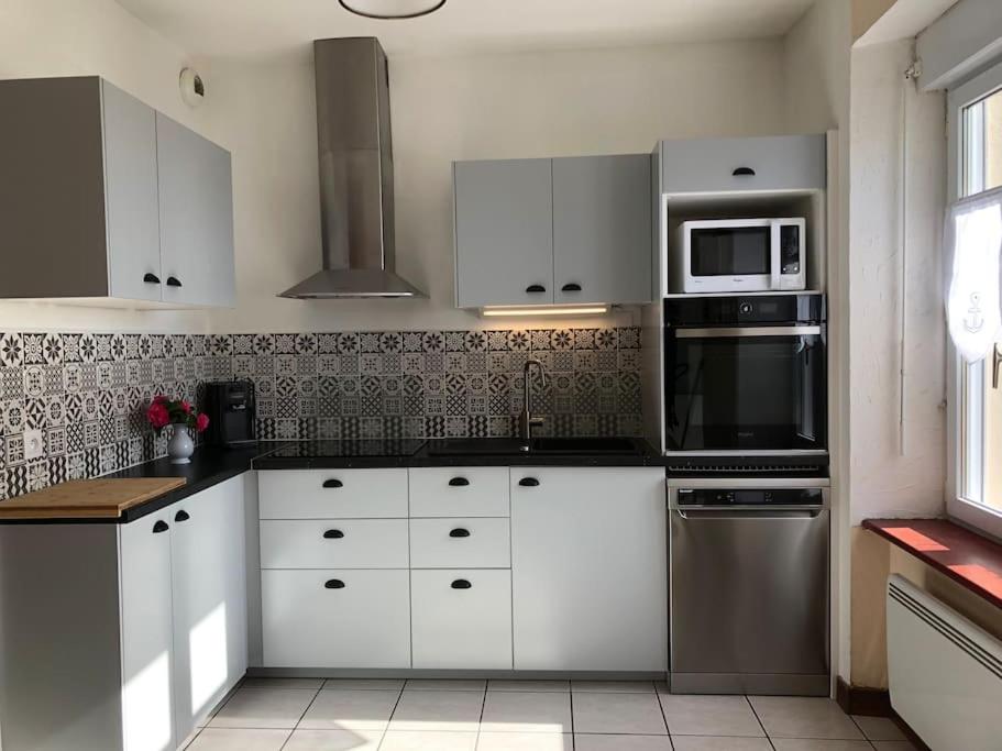 a kitchen with white cabinets and stainless steel appliances at Kerletty, la mer, les embruns, à 250 m des plages in Plouguerneau