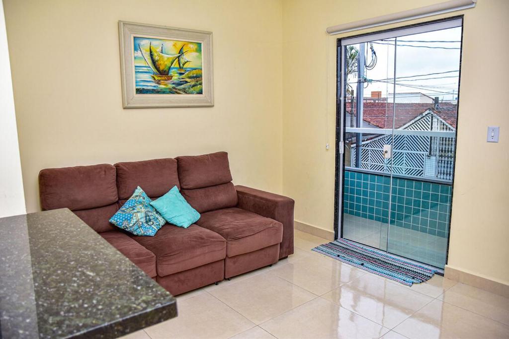 uma sala de estar com um sofá castanho e uma janela em Casa com Wi-Fi a 400 metros da Praia Maracanã-SP em Solemar