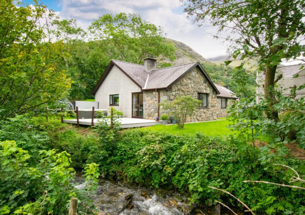 a stone house in the middle of a forest at Swn y Nant in Dinorwic