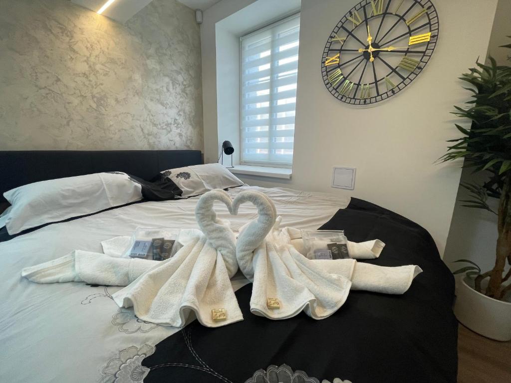 Designový apartmán v centru Liberce في ليبيريتس: سرير بمناشف بيضاء وساعة على الحائط