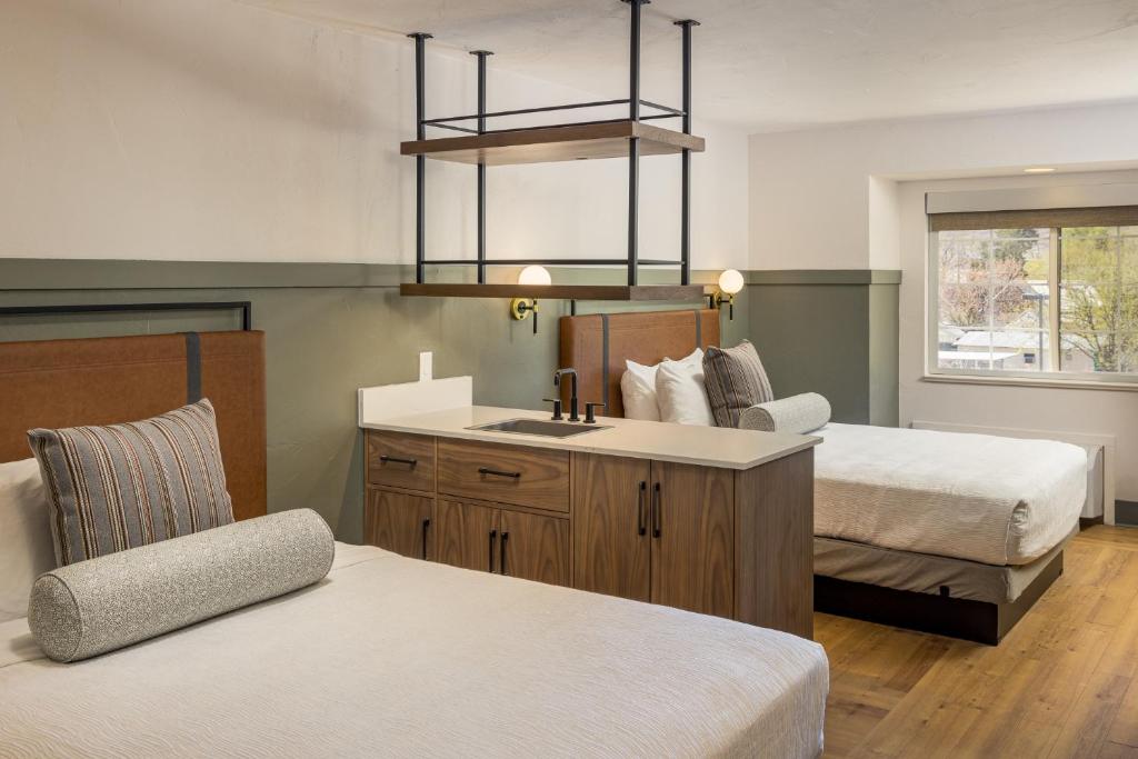 a bedroom with two beds and a sink and a chair at River Canyon Lodge in Moab