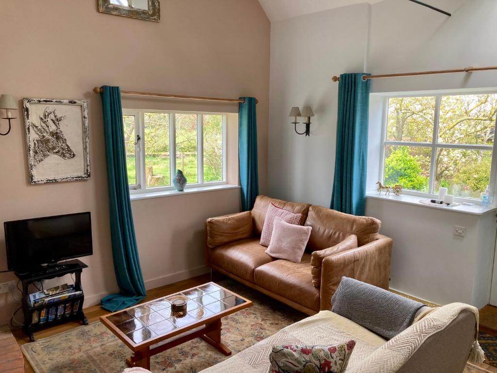 a living room with a couch and a tv at Simpers Drift, Great Glemham in Saxmundham