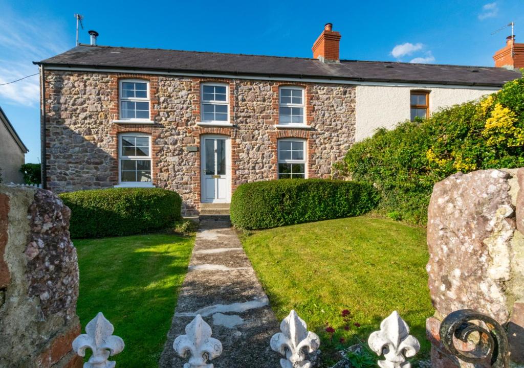 an old stone house with a garden in front of it at West End Cottage in Llangennith