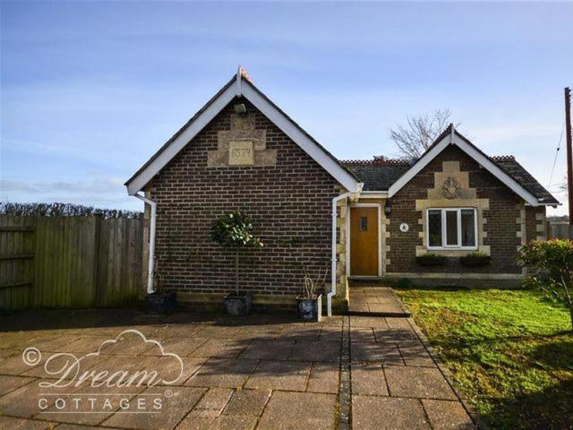 een stenen huis met een gele deur in een tuin bij Frome Lodge House in Dorchester