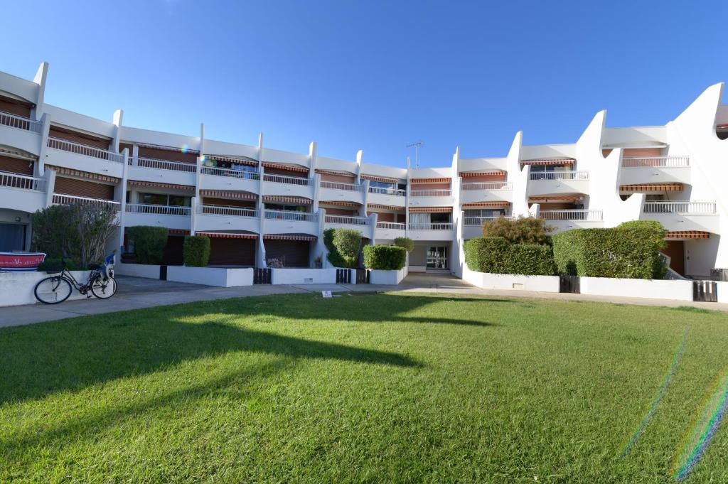 une cour vide d'un immeuble d'appartements avec une cour herbeuse dans l'établissement Appartement donnant sur le port de plaisance de Port Camargue et a proximité des plages, au Grau-du-Roi