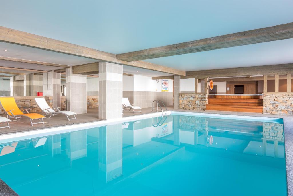 a swimming pool with blue water in a building at Sun Valley Residence in La Plagne