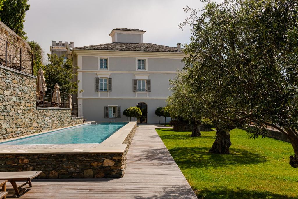 a villa with a swimming pool in front of a building at Aethos Corsica in Oletta