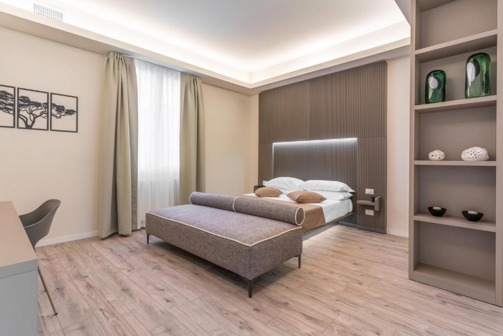 una camera con letto e ottomana di Meneghina Suites Foresteria Lombarda a Milano