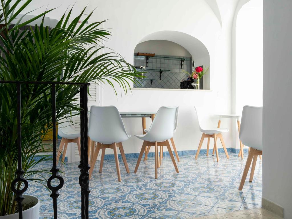 a dining room with white chairs and a table with a mirror at Albergo La Prora in Capri