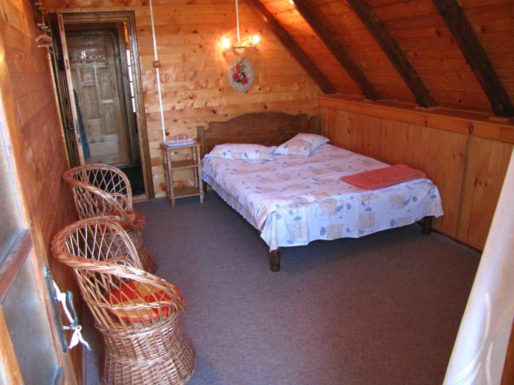 um quarto com uma cama e 2 cadeiras de vime em Casa Oana em Sulina