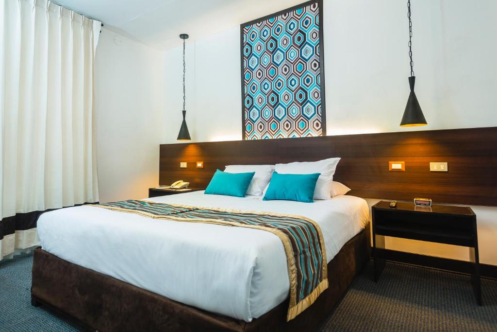 Habitación de hotel con cama grande con almohadas azules en SACHA Centric, en Cusco