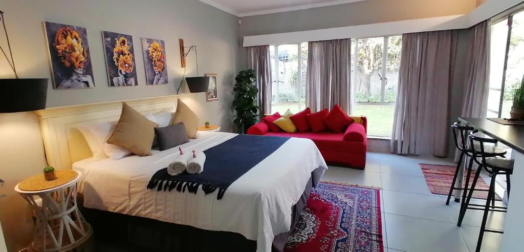 a bedroom with a large bed and a red couch at The Hancock Inn in Klerksdorp