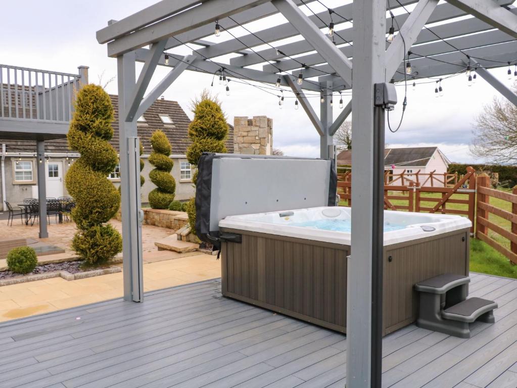 a hot tub on a deck with a pergola at The Hideaway in Magherafelt