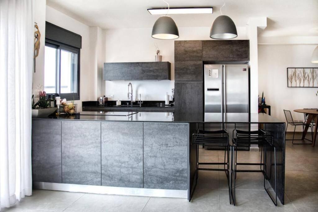 a kitchen with a black counter and a refrigerator at A large and well-designed apartment with a stunning view in Or ‘Aqīvāh