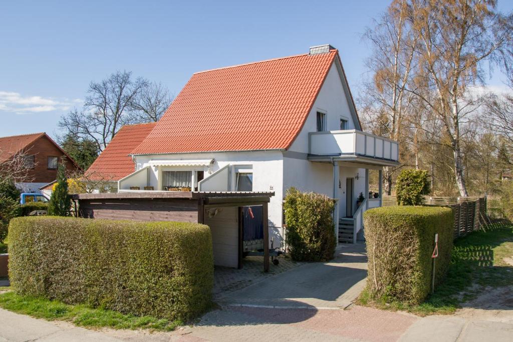 a white house with an orange roof and some bushes at Haus Stricker in Sagard